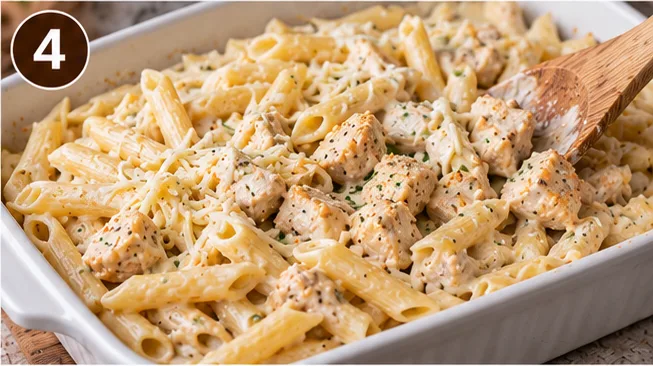 Pasta, chicken, and Alfredo sauce mixed together in a baking dish before baking