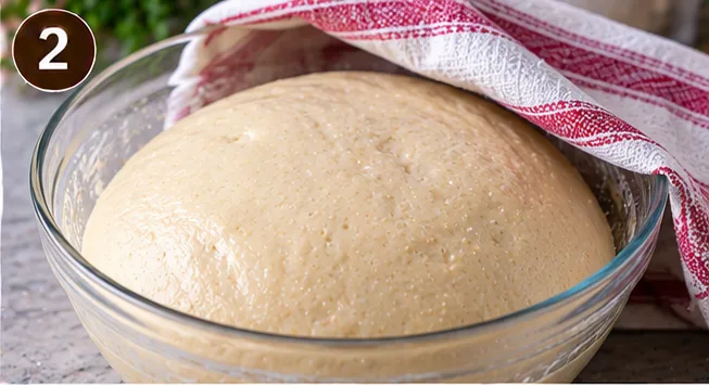 Yeasted dough doubled in size in a bowl after its first rise
