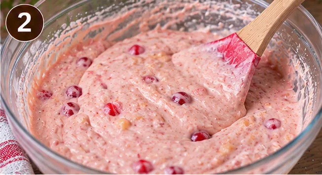 Pink maraschino cherry cake batter mixed together in a glass bowl