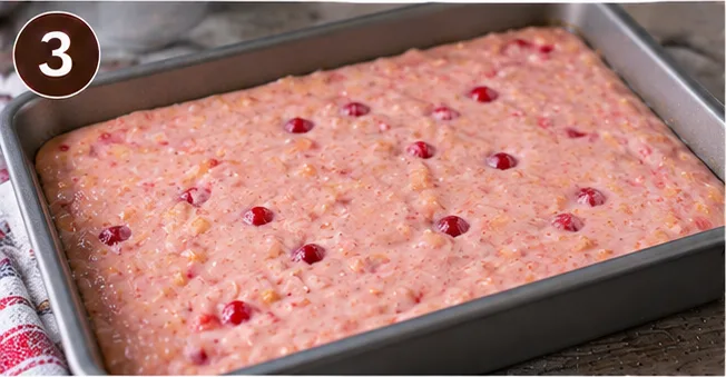 Maraschino cherry cake batter with cherries poured into a baking pan