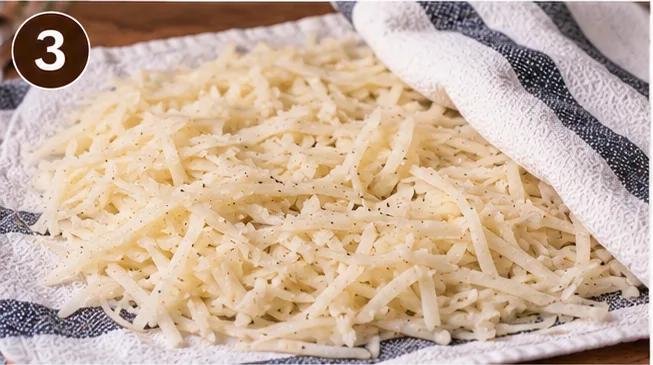 Rinsed and dried shredded potatoes spread on a kitchen towel