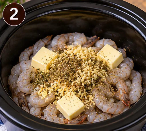 Shrimp topped with butter, minced garlic, and Italian seasoning in the slow cooker before cooking