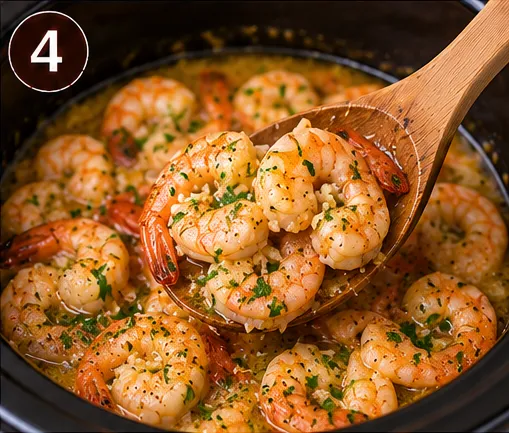 A wooden spoon lifting garlic butter shrimp garnished with parsley from the slow cooker